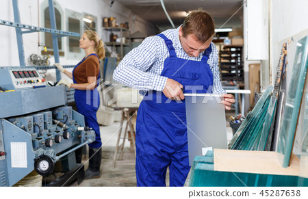 Male glazier measuring glass with tape measure 45287638