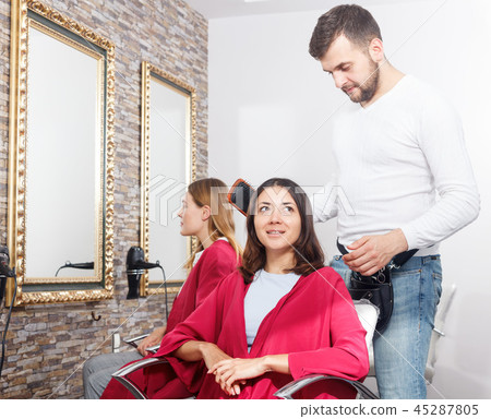 Young man professional hairdresser cut female's hair in salon Young man professional hairdresser cut female's hair in salon 45287805