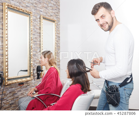 Young man professional hairdresser cut female's hair in salon 45287806