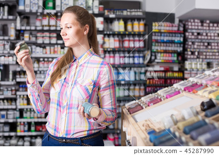 woman customer holding glass jar with color paint in art department 45287990
