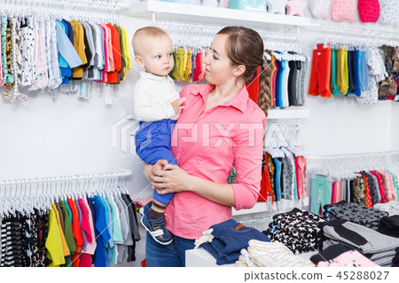 Young mother is choosing new clothes for her son in the kid store. 45288027