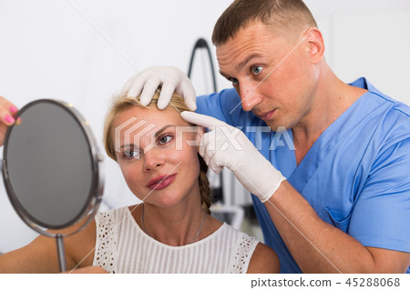 Man doctor is preparing female patient to procedure 45288068