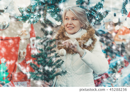 Adult woman is choosing decorative Christmas tree in the market 45288236
