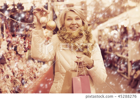 Woman is preparing for Christmas and choosing balls on the tree 45288276