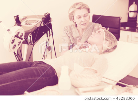 Cosmetologist examining face of young woman Cosmetologist examining face of young woman 45288300