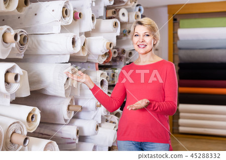 Female shop assistant demonstrating assortment at textile shop Female shop assistant demonstrating assortment at textile shop 45288332
