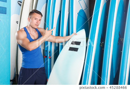 man choosing surf equipment in surf club 45288466