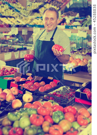 Smiling male seller is standing with box with tomatos Smiling male seller is standing with box with tomatos 45288838