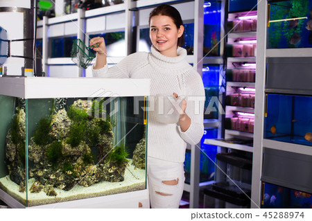 Smiling girl is keeping aquarium net and water container next to Smiling girl is keeping aquarium net and water container next to 45288974
