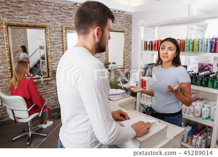 Man talking with girl consultant about services at salon Man talking with girl consultant about services at salon 45289014