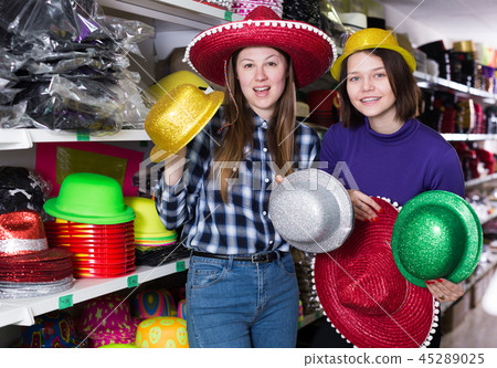 Female friends choosing funny headdresses in store Female friends choosing funny headdresses in store 45289025