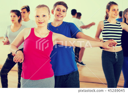 Group of admiring teenagers dancing tango in dance studio Group of admiring teenagers dancing tango in dance studio 45289045
