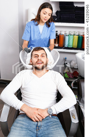 Portrait of woman hairdresser in gloves washing hair of smiling man in salon Portrait of woman hairdresser in gloves washing hair of smiling man in salon 45289046