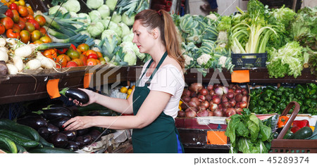 Saleswoman holding aubergine in market 45289374