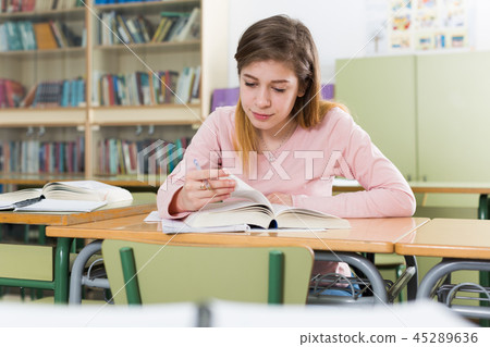 Girl is sitting at the desk and writing homework 45289636