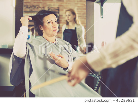 Angry woman telling to hairdresser that she does not like her hairstyle 45289651