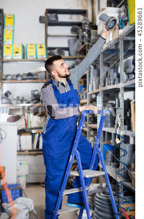 Male worker deciding on flexible ventilation pipe in workshop 45289661