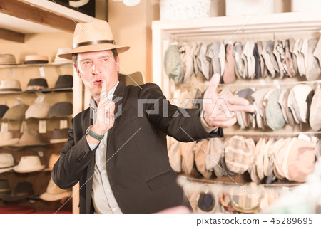 portret of smiling young guy try on panama at headwear store 45289695