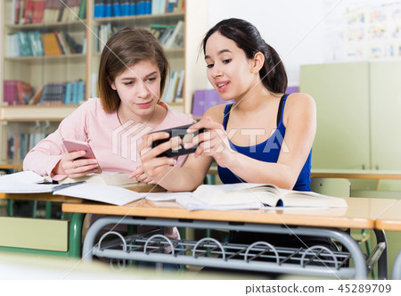 Young girls are talking about boys with phone in the classroom 45289709