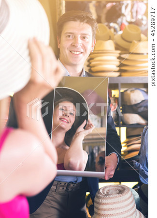 guy holding mirror and showing female his reflection in hats shopping mall guy holding mirror and showing female his reflection in hats shopping mall 45289717