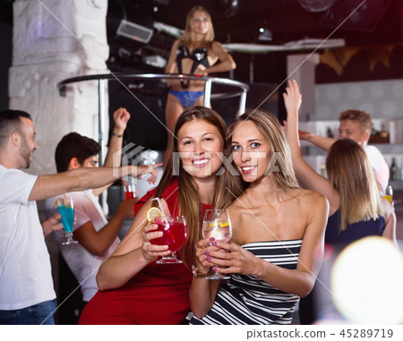 smiling women dancing in the night club with drinks in the hand smiling women dancing in the night club with drinks in the hand 45289719