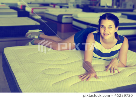 woman is lying on bed and testing mattress in the store. woman is lying on bed and testing mattress in the store. 45289720