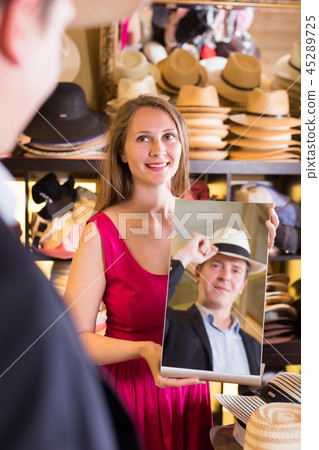 female holding mirror and showing male his reflection in hats shopping mall 45289725