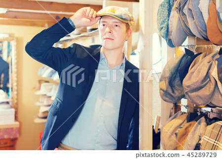 portrait of young male try on newboy cap at the shopping mall portrait of young male try on newboy cap at the shopping mall 45289729