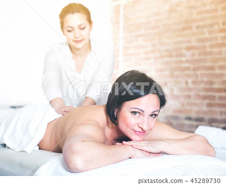 Massagist massaging back area of woman Massagist massaging back area of woman 45289730