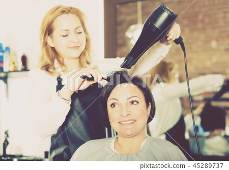 Hairdresser styling hair to adult woman Hairdresser styling hair to adult woman 45289737
