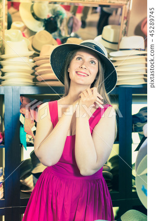 young blonde woman choose straw hat in shop young blonde woman choose straw hat in shop 45289745