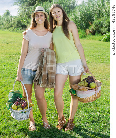 two girls standing with baskets for picnic two girls standing with baskets for picnic 45289746