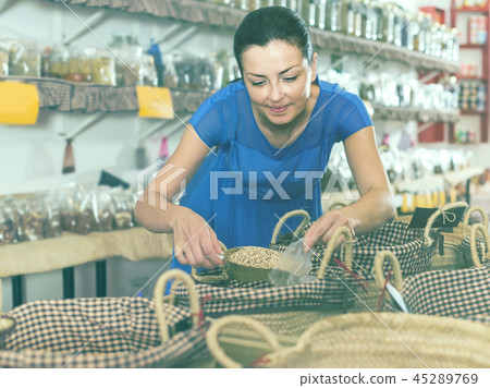 woman taking dried beans with shovel from backet in organic shop 45289769