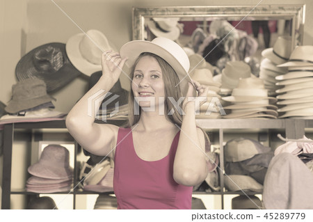 young blonde woman choose straw hat in shop young blonde woman choose straw hat in shop 45289779