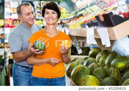 Adult male and female are choosing green melons in the store. Adult male and female are choosing green melons in the store. 45289910