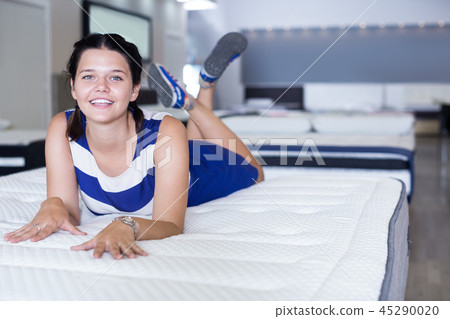 Woman lying on soft mattress and smiling in store Woman lying on soft mattress and smiling in store 45290020
