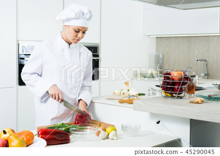Young woman cook preparing vegetables in white uniform Young woman cook preparing vegetables in white uniform 45290045