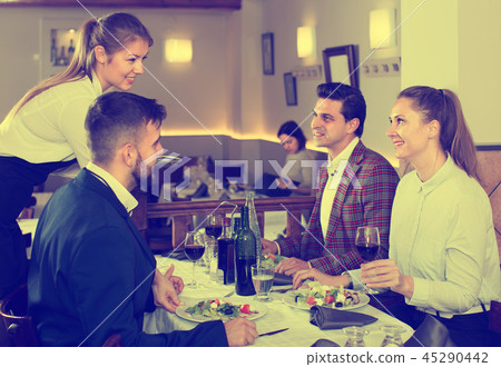 friendly waitress bringing delicious salads to smiling people at restaurant 45290442