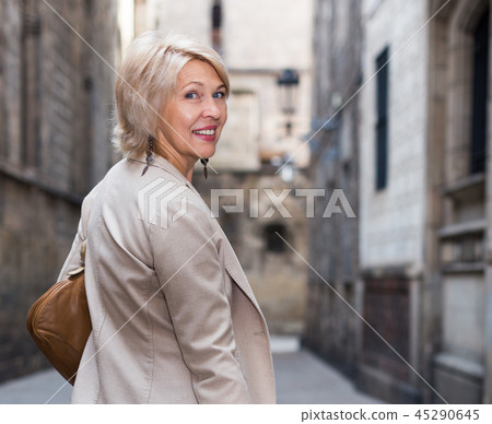 Cheerful mature female is walking in classic jacket Cheerful mature female is walking in classic jacket 45290645