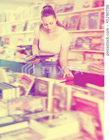 Young cheerful woman buying books in hard cover Young cheerful woman buying books in hard cover 45290706