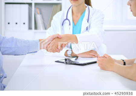 Doctor and patient shaking hands. Family couple at medical exam, just hands at the table. Medicine 45293938