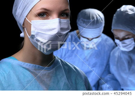 Medical team performing operation. Focus at female doctor Medical team performing operation. Focus at female doctor 45294045