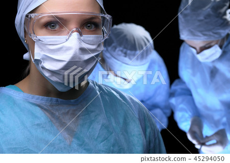 Medical team performing operation. Focus at female doctor Medical team performing operation. Focus at female doctor 45294050