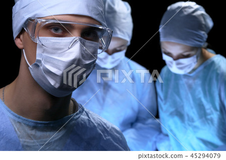 Medical team performing operation. Focus at female doctor Medical team performing operation. Focus at female doctor 45294079