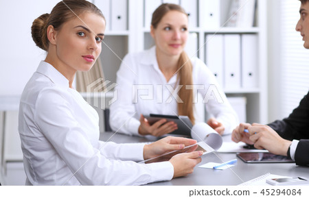 Group of business people at meeting on the background of office. Focus at a beautiful brunette woman Group of business people at meeting on the background of office. Focus at a beautiful brunette woman 45294084