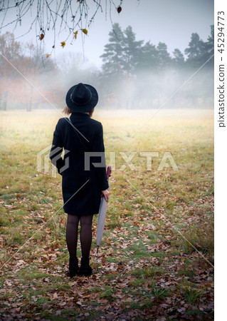 Woman in a black coat in foggy weather 45294773