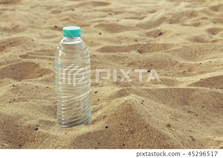 Bottled water on a hot day at the beach.Plastic bottle with clear water to drink, on sea background Bottled water on a hot day at the beach.Plastic bottle with clear water to drink, on sea background 45296517