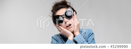 Young brunette girl in black glasses. Cat glasses. The hair is gathered in a bun. The girl is 45299990