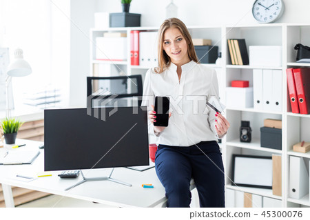 A young girl sat down on the table and holding a phone and a Bank card. A young girl sat down on the table and holding a phone and a Bank card. 45300076