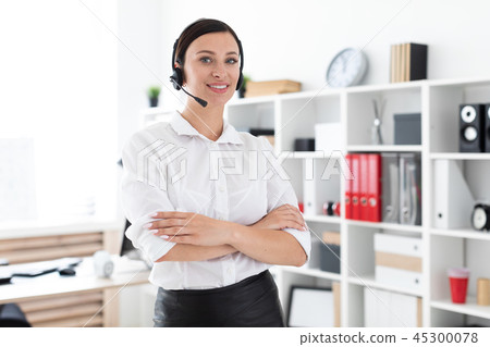 A young girl in headphones with a microphone is in a bright office. A young girl in headphones with a microphone is in a bright office. 45300078